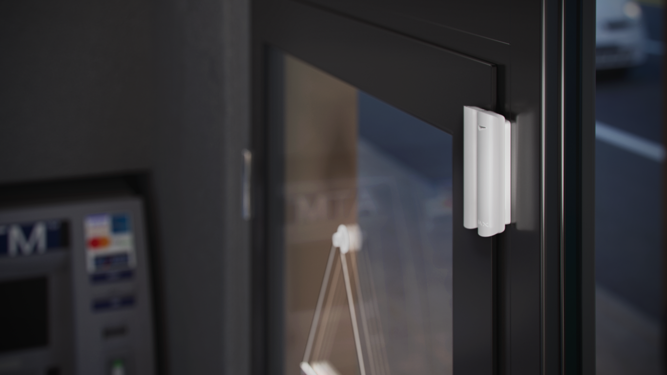 Magnetkontaktmelder Türgriff an einer Glas- und Metalltür, im Hintergrund.