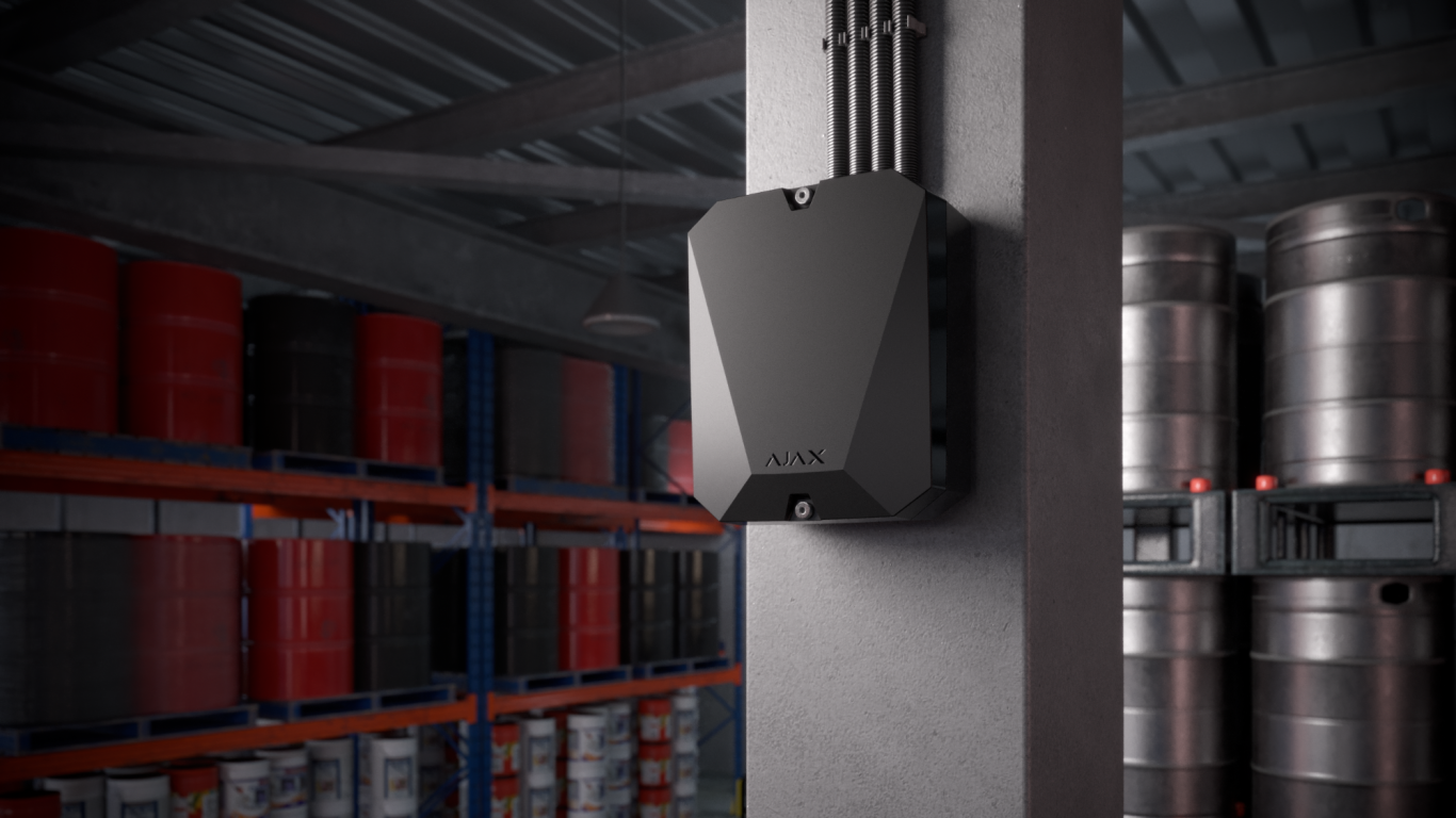 Vorschaubild Lagerhalle Schwarzes Gehäuse an einer Lagerhallenwand neben Edelstahlfässern.